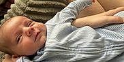 Weston is registered to the contest to win money with this photo: baby, infant, person, clothing, onesie, striped, cushion, blanket, hand, legs, skin, home, relaxing, comfort, portrait, closeup, cute, expression, sleepwear, resting