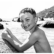 Jules participe au concours pour gagner de l'argent avec cette photo : boy, child, smile, water, rock, outdoor, beach, portrait, black_and_white, happy, wet_hair, nature, sunlight, shoreline, youth, summer, playful, bare_chest, scenic, leisure