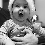 Louis a rejoint le concours — aidez-le/la à gagner de superbes lots ! baby, child, infant, person, hat, hand, smile, surprised, indoor, blurred_background, monochrome, clothing, holding, cute, young, portrait, happy, face, expression, cozy
