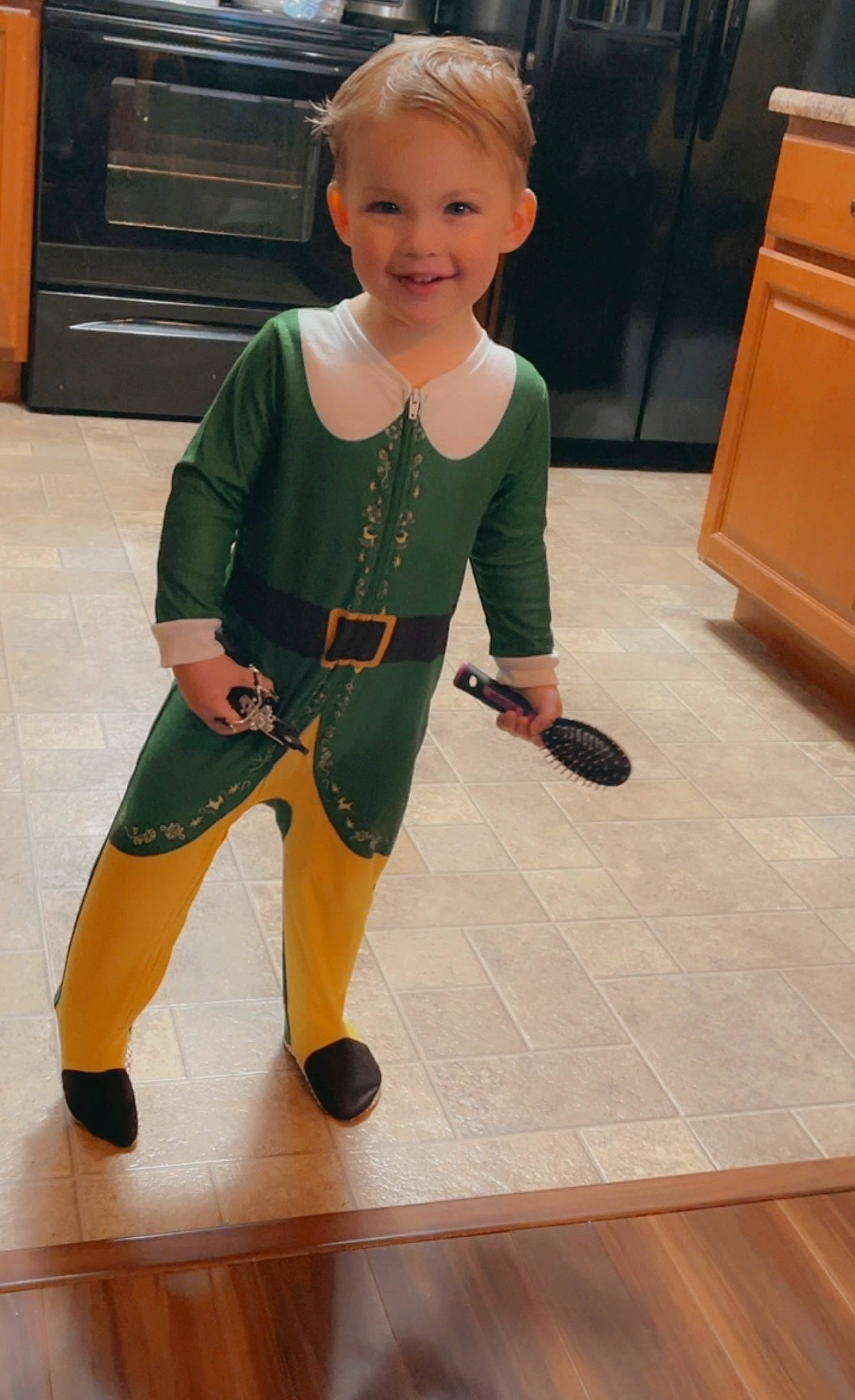 Logan is registered to the contest to win money with this photo: baby_toddler_clothing, cabinetry, child, drawer, face, floor, flooring, hardwood, head, human_leg, joy, knee, leg, person, sleeve, smile, sportswear, thigh, toddler, varnish