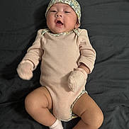 Hawika is registered to the contest to win money with this photo: adorable, baby, child, comfortable, cute, expression, floral_pattern, hat, headwear, indoors, infant, lying_down, mittens, newborn, person, pink_clothing, portrait, skin, socks, soft_fabric