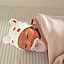 Hawika is registered to the contest to win money with this photo: baby, blanket, child, cute, face, hat, headwear, indoors, infant, lying_down, newborn, pacifier, peaceful, pink, sleepwear, soft_texture, strawberry_pattern, striped_bed, white, wrapped