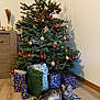 Arnold participe au concours pour gagner de l'argent avec cette photo : christmas_tree, cat, tabby_cat, presents, gifts, holiday_decorations, ornaments, living_room, wooden_floor, festive, indoor, relaxed_cat, decorated_tree, holiday, celebration, christmas, pets, animal, cozy, festivity