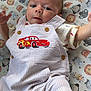 Carter is registered to the contest to win money with this photo: baby, child, infant, overalls, striped_clothing, red_car_patch, animal_pattern, play_mat, cute, lying_down, raised_arm, curious_expression, indoor, soft_lighting, baby_clothes, child_fashion, smiling_face, head, person, young_child