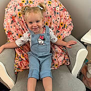 Lily is registered to the contest to win money with this photo: toddler, child, smiling, pigtails, overalls, minnie_mouse, pink_shoes, armchair, blanket, floral_pattern, indoor, happy, cute, person, clothing, hair_bows, seated, portrait, cozy, furniture