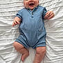 Oliver is registered to the contest to win money with this photo: baby, infant, smiling, romper, blue_clothing, blanket, white, happy, cute, child, lying_down, skin, face, legs, arms, fingers, feet, indoor, portrait, expression