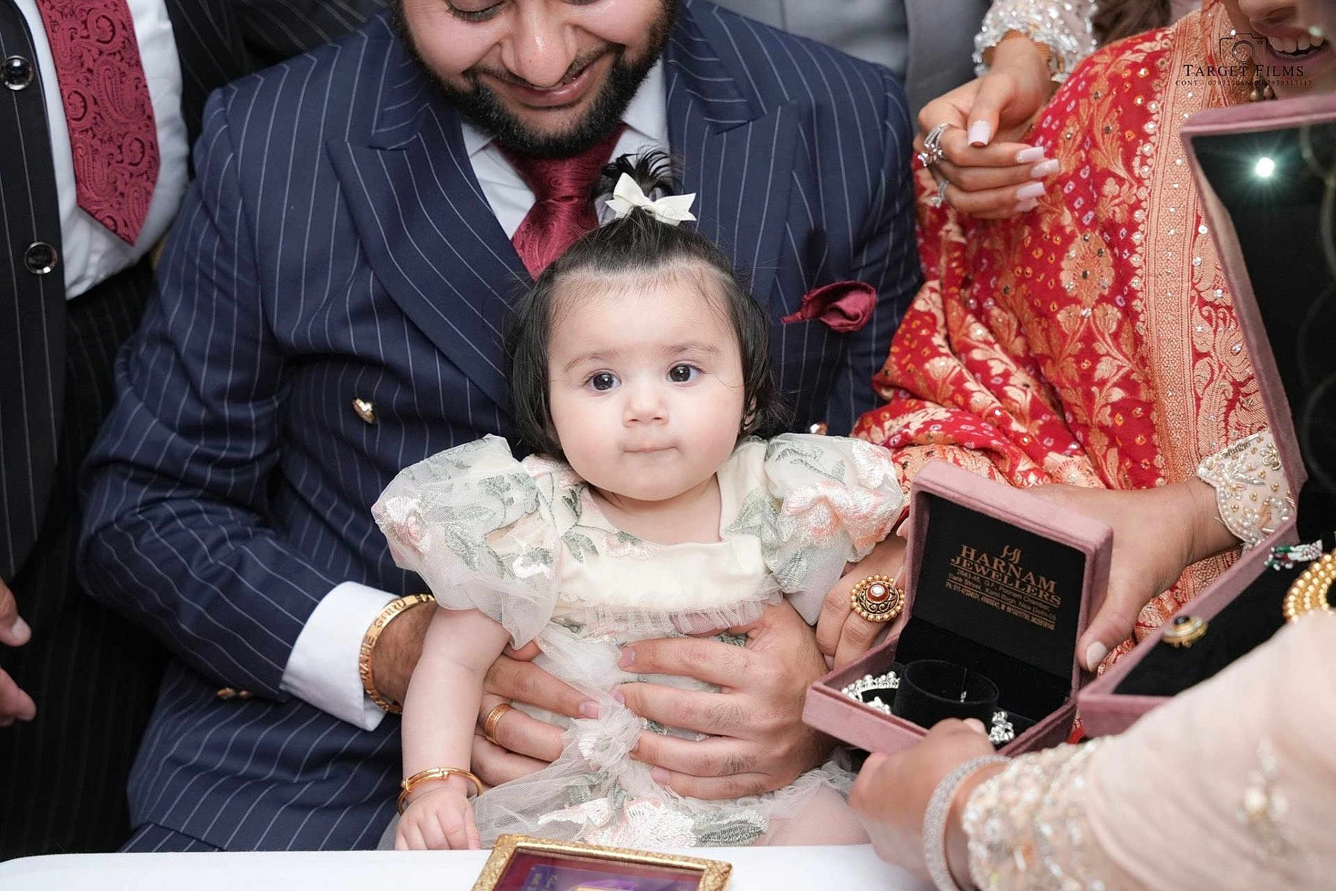 Tanisha is registered to the contest to win money with this photo: baby, child, man, suit, tie, jewelry, rings, bracelet, dress, floral, celebration, hands, portrait, traditional_clothing, table, people, event, happy, family, indoor