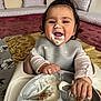 Tanisha joined the competition — help win amazing prizes! baby, highchair, food, messy_face, yogurt, spoon, smiling, indoor, child, bib, happy, feeding, infant, couch, cushion, carpet, person, clothing, playful, tongue_out