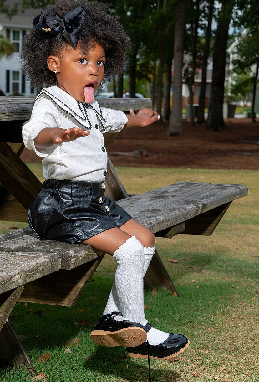 Khloe is registered to the contest to win money with this photo: child, child_model, footwear, furniture, hairstyle, knee, leg, leisure, person, photography, shoe, sitting, surprise