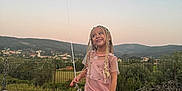 Elaïa a rejoint le concours — aidez-le/la à gagner de superbes lots ! balloon, braids, casual_clothing, child, fence, girl, happy, hills, holding, landscape, nature, outdoor, pavement, person, pink_dress, sandals, sky, smile, standing, sunset
