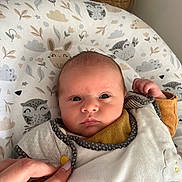 Arthur a rejoint le concours — aidez-le/la à gagner de superbes lots ! baby, infant, face, hand, clothing, bib, cushion, pattern, animal_print, indoor, portrait, newborn, soft_texture, human, person, cute, expression, bedroom, fabric, comfort