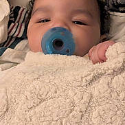 Ryan is registered to the contest to win money with this photo: baby, pacifier, blanket, hand, face, sleepy, cozy, infant, child, curly_hair, soft_texture, comfort, closeup, indoor, portrait, cute, resting, warm, nursery, peaceful