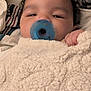 baby, pacifier, blanket, hand, face, sleepy, cozy, infant, child, curly_hair, soft_texture, comfort, closeup, indoor, portrait, cute, resting, warm, nursery, peaceful