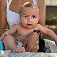 Alina participe au concours pour gagner de l'argent avec cette photo : baby, child, adult, person, outdoor, nature, sunlight, skin, face, arm, bracelet, white_clothing, diaper, tablecloth, blurred_background, curious_expression, sitting, holding, portrait, summer