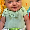 baby, smiling, infant, child, green_clothing, baby_seat, harness, cute, happy, portrait, colorful_background, playful, baby_boy, sitting, closeup, childcare, indoors, small_child, face, young