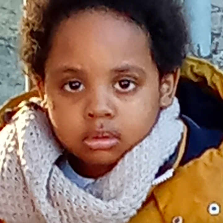 Emmanuel Jess a rejoint le concours — aidez-le/la à gagner de superbes lots ! brown_skin, casual_photo, child, close_up, curly_hair, face, head_and_shoulders, jacket, outdoor, person, portrait, scarf, serious_expression, standing, textured_wall, warm_clothing, winter_clothing, yellow_jacket, young_child