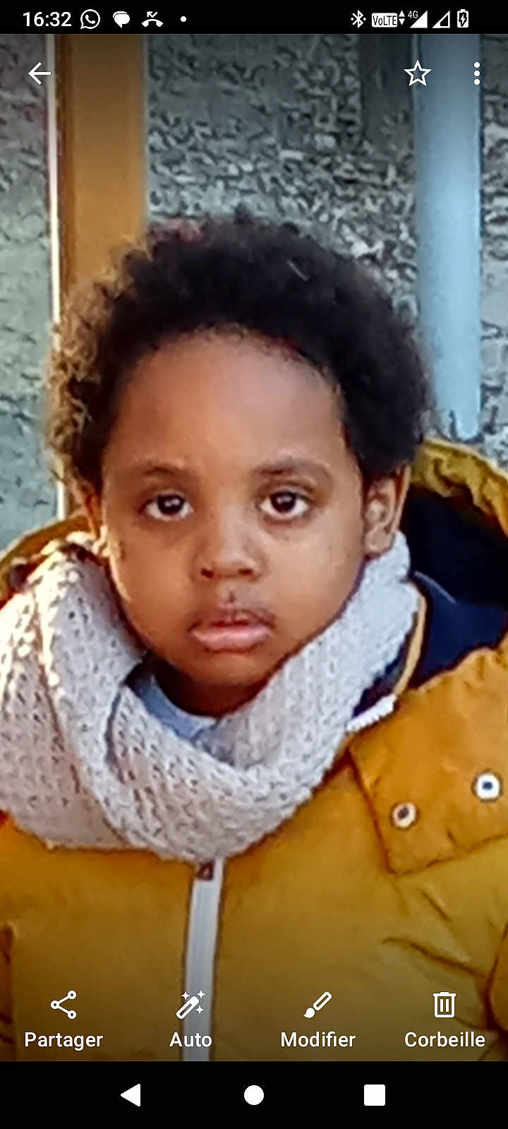 Emmanuel Jess a rejoint le concours — aidez-le/la à gagner de superbes lots ! child, face, scarf, jacket, yellow_jacket, curly_hair, outdoor, portrait, young_child, winter_clothing, serious_expression, person, standing, casual_photo, textured_wall, warm_clothing, close_up, head_and_shoulders, brown_skin