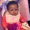 Roslynn joined the competition — help win amazing prizes! baby, infant, child, portrait, smiling, sitting, red_clothing, pink_bib, polka_dots, pacifier, teething_toy, beaded_chain, car_seat, blanket, cushion, indoor, close_up, face, curly_hair, happy