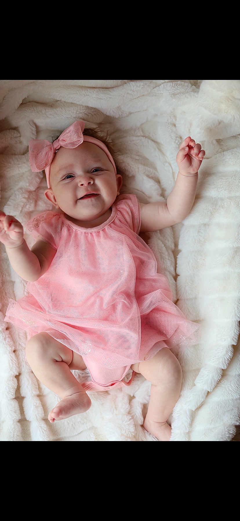 Milani is registered to the contest to win money with this photo: baby, infant, pink_dress, headband, bow, smiling, lying_down, blanket, soft_texture, cute, happy, child, toddler, skin, small_hands, feet, portrait, indoors, cozy, adorable