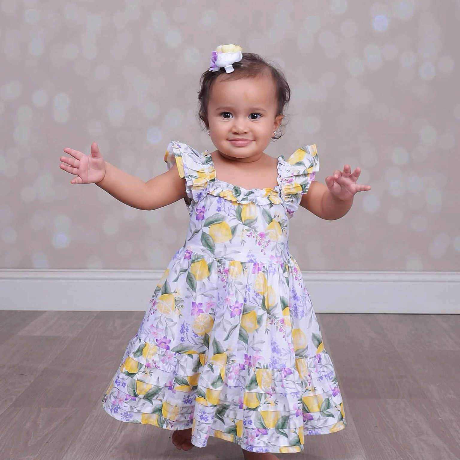 Basma joined the competition — help win amazing prizes! arms_outstretched, baby, barefoot, bokeh_background, child, cute, dress, fashion, floral_pattern, flower_clip, girl, hair_accessory, happy, indoor, innocence, portrait, smiling, standing, toddler, wooden_floor