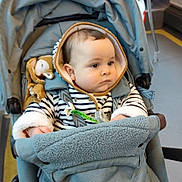 Waël a rejoint le concours — aidez-le/la à gagner de superbes lots ! baby, infant, stroller, hood, striped_clothing, plush_toy, pacifier, seat, harness, hand, cozy_blanket, teal_stroller, public_transport, bus_interior, adult, jacket, floor, straps, portrait, neutral_expression