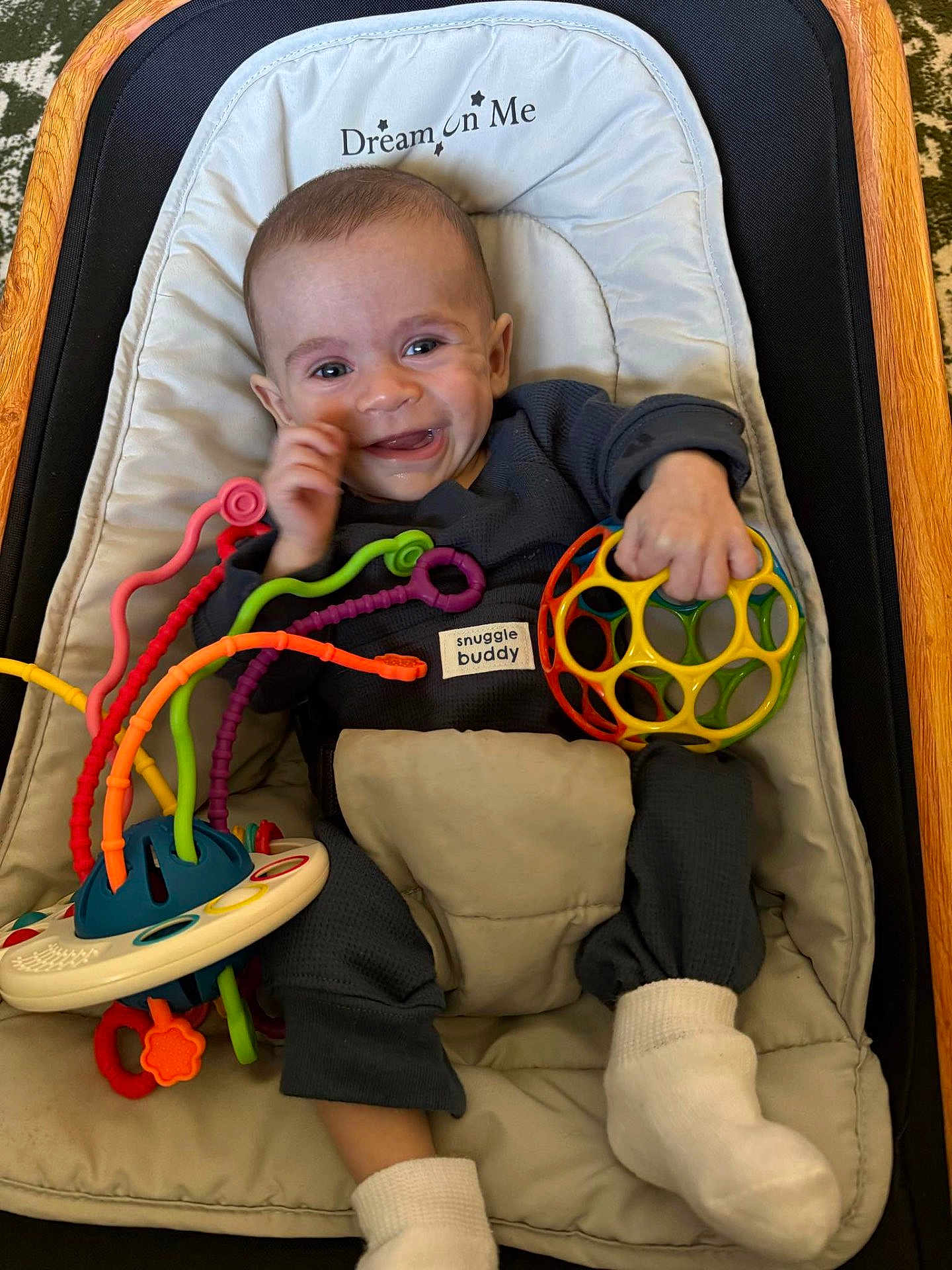 Huxley is registered to the contest to win money with this photo: baby, smiling, toy, baby_chair, cushion, clothing, sock, infant, face, hand, footwear, indoor, play, colorful, happy, cute, child, person, fabric, seat