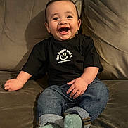 Hudson is registered to the contest to win money with this photo: baby, casual_wear, child, clothing, couch, cute, face, feet, hands, happy, indoor, infant, jeans, joyful, person, portrait, sitting, smiling, socks, tshirt