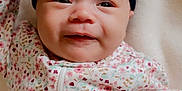Layla is registered to the contest to win money with this photo: baby, infant, face, headband, bow, floral_pattern, onesie, clothing, blanket, soft, cute, portrait, child, newborn, smile, lying_down, closeup, skin, expression, indoors