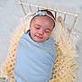 baby, sleeping, blue_blanket, headband, knitted_throw, white_bed, peaceful, newborn, portrait, infant, soft_texture, cozy, cute, resting, wrapped, child, indoor, decor, calm, adorable