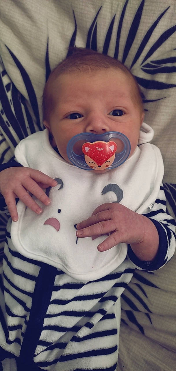 Tylian participe au concours pour gagner de l'argent avec cette photo : baby, baby_toddler_clothing, cheek, collar, comfort, eye, eyelash, finger, gesture, happy, iris, lip, mouth, nose, outerwear, person, skin, sleeve, textile, thumb