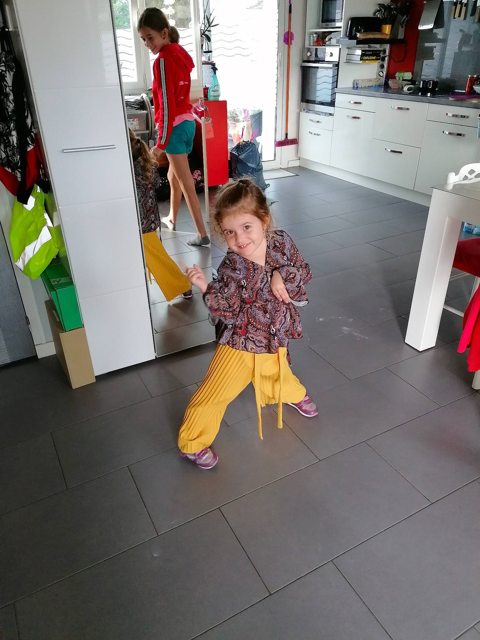 Lilas participe au concours pour gagner de l'argent avec cette photo : bag, child, cleanliness, costume, floor, flooring, foot, fun, human_leg, joy, leisure, luggage_and_bags, person, play, room, sandal, shorts, sidewalk, street, t_shirt