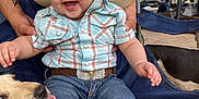 Josiah is registered to the contest to win money with this photo: baby, child, smiling, hat, cowboy_hat, plaid_shirt, jeans, boots, dog, hand, outdoor, chair, belt, happy, person, pet, face, grass, furniture, tattoo