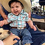 baby, child, smiling, hat, cowboy_hat, plaid_shirt, jeans, boots, dog, hand, outdoor, chair, belt, happy, person, pet, face, grass, furniture, tattoo