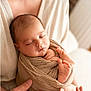 newborn, baby, swaddle, sleeping, infant, parent_hands, mother, portrait, soft_light, neutral_tones, cozy, tiny_toes, fingers, blanket, indoor, brick_wall, close_up, tender, studio_style, screenshot