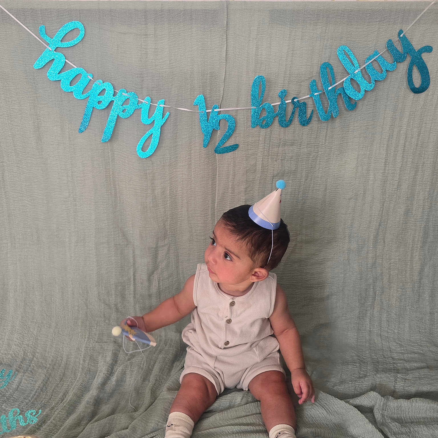 Faris joined the competition — help win amazing prizes! baby, background, banner, birthday, celebration, child, cute, decor, half_birthday, happy, indoors, infant, milestone, one_half, party_hat, portrait, sitting, small_object, sock, textile