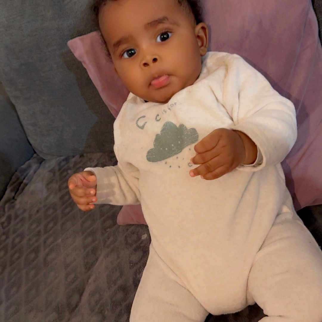 Yassin participe au concours pour gagner de l'argent avec cette photo : baby, child, clothing, couch, cute, expression, eyes, face, furniture, hair, hand, indoor, infant, onesie, person, pillow, portrait, relaxing, skin, young