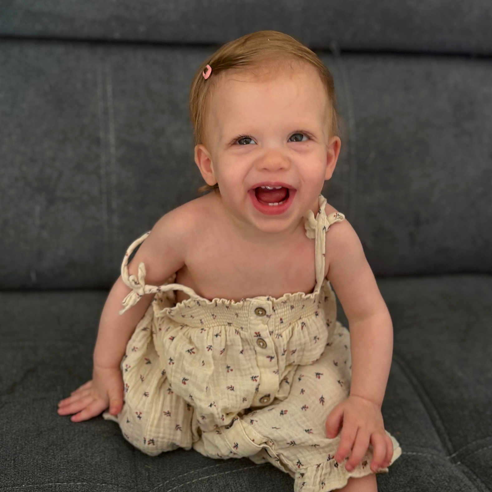 Athena participe au concours pour gagner de l'argent avec cette photo : baby, button, child, clothing, comfort, couch, cute, dress, fabric, face, hair_clip, happy, indoor, joy, person, sitting, skin, smiling, toddler, young