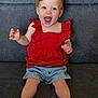 baby, toddler, child, smiling, happy, sitting, red_top, denim_shorts, sandals, indoor, couch, furniture, cute, portrait, young_child, joyful, small_child, casual_clothing, person, cheerful