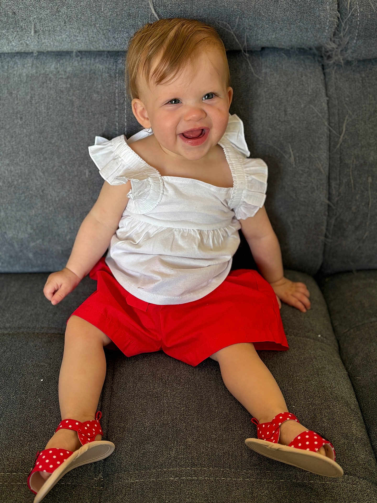 Esmeralda a rejoint le concours — aidez-le/la à gagner de superbes lots ! toddler, child, smiling, happy, sitting, couch, white_top, red_shorts, red_sandals, polka_dot, footwear, indoor, person, face, cute, clothing, baby, comfortable, casual, joyful