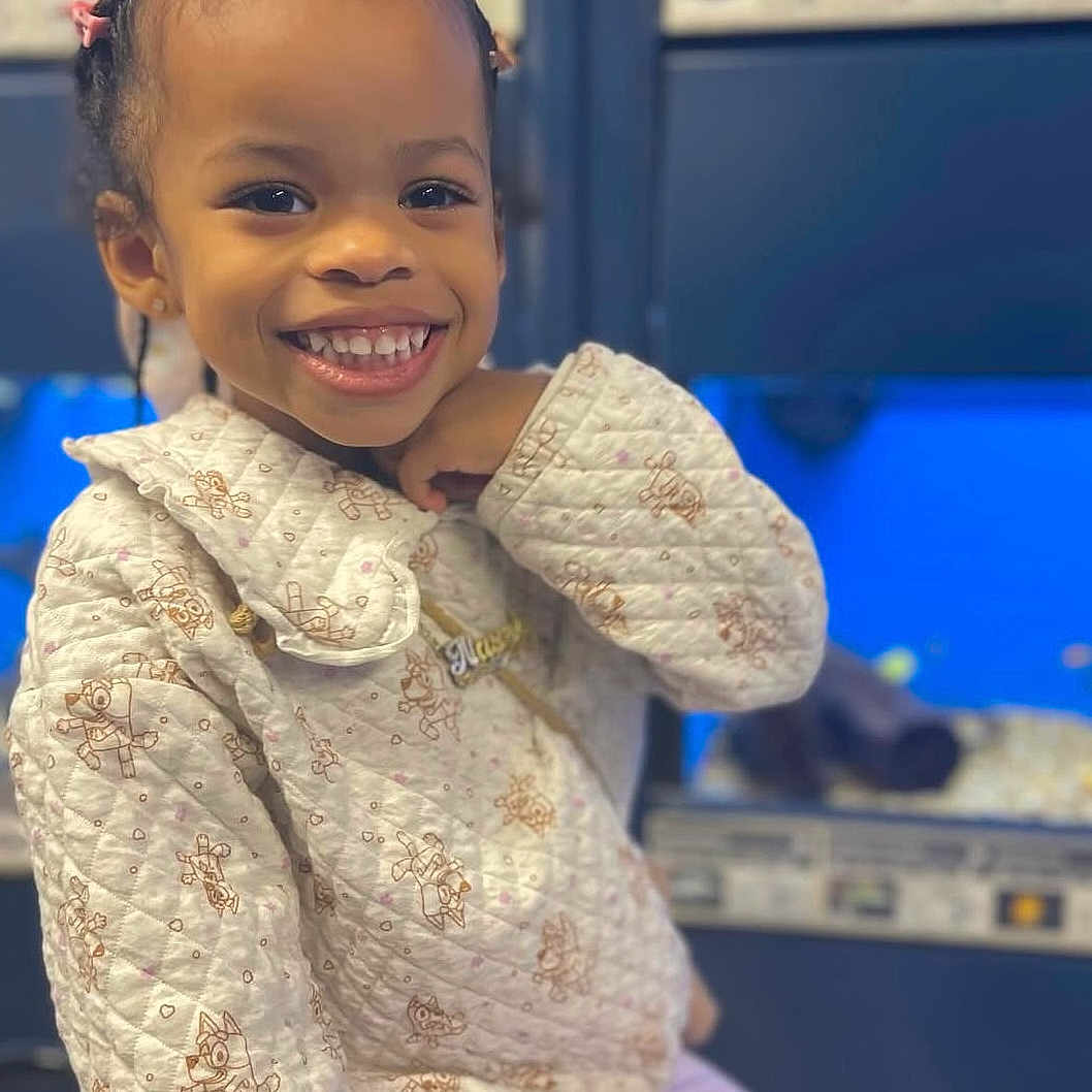 Nayeli Skye joined the competition — help win amazing prizes! background, braided_hair, casual_wear, child, closeup, cozy, cute, face, fashion, girl, happy, indoor, patterned_clothing, person, pink_clips, portrait, quilted_jacket, sitting, smiling, young