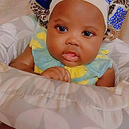 Thiea is registered to the contest to win money with this photo: baby, infant, child, bonnet, cushion, seated, indoors, clothing, face, portrait, cute, looking, hand, skin, headwear, young, expression, soft, comfort, resting