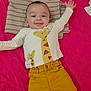 baby, child, smiling, giraffe_print, yellow_pants, striped_pillow, pink_background, happy, lying_down, infant, cute, clothing, person, portrait, indoors, arms_outstretched, head, face, young_child, resting
