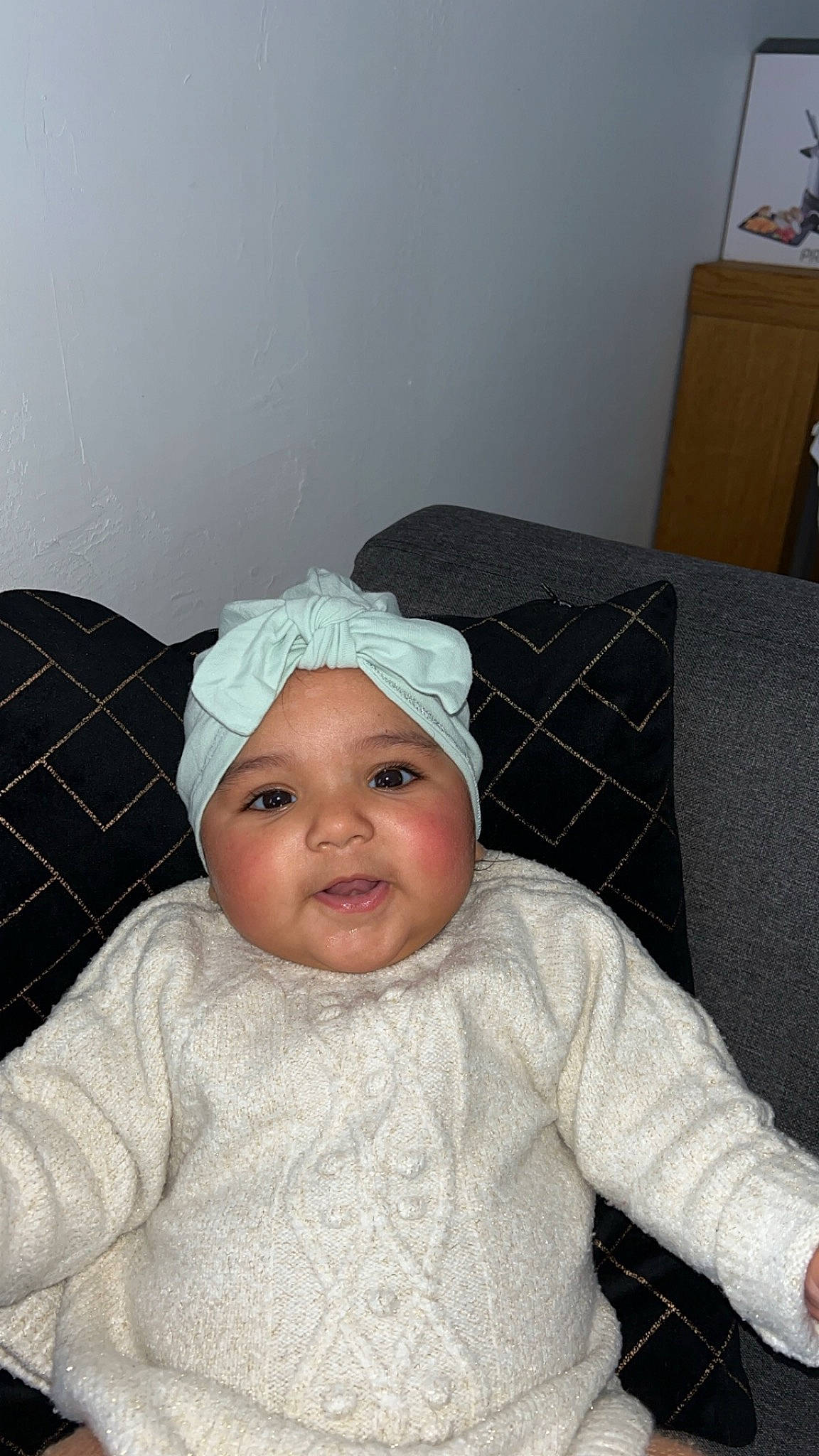 Julyana participe au concours pour gagner de l'argent avec cette photo : baby, baby_toddler_clothing, bonnet, box, cap, cheek, child, comfort, flooring, headgear, headwear, linens, pattern, person, room, shipping_box, sitting, sleeve, smile, toddler
