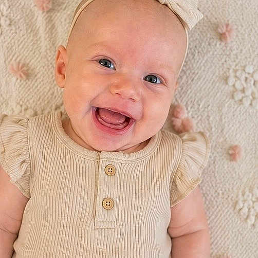 Scout joined the competition — help win amazing prizes! baby, smiling, headband, bow, infant, cute, portrait, face, happy, child, cream, textured_blanket, buttoned_shirt, soft_lighting, closeup, skin, person, indoors, young, joyful
