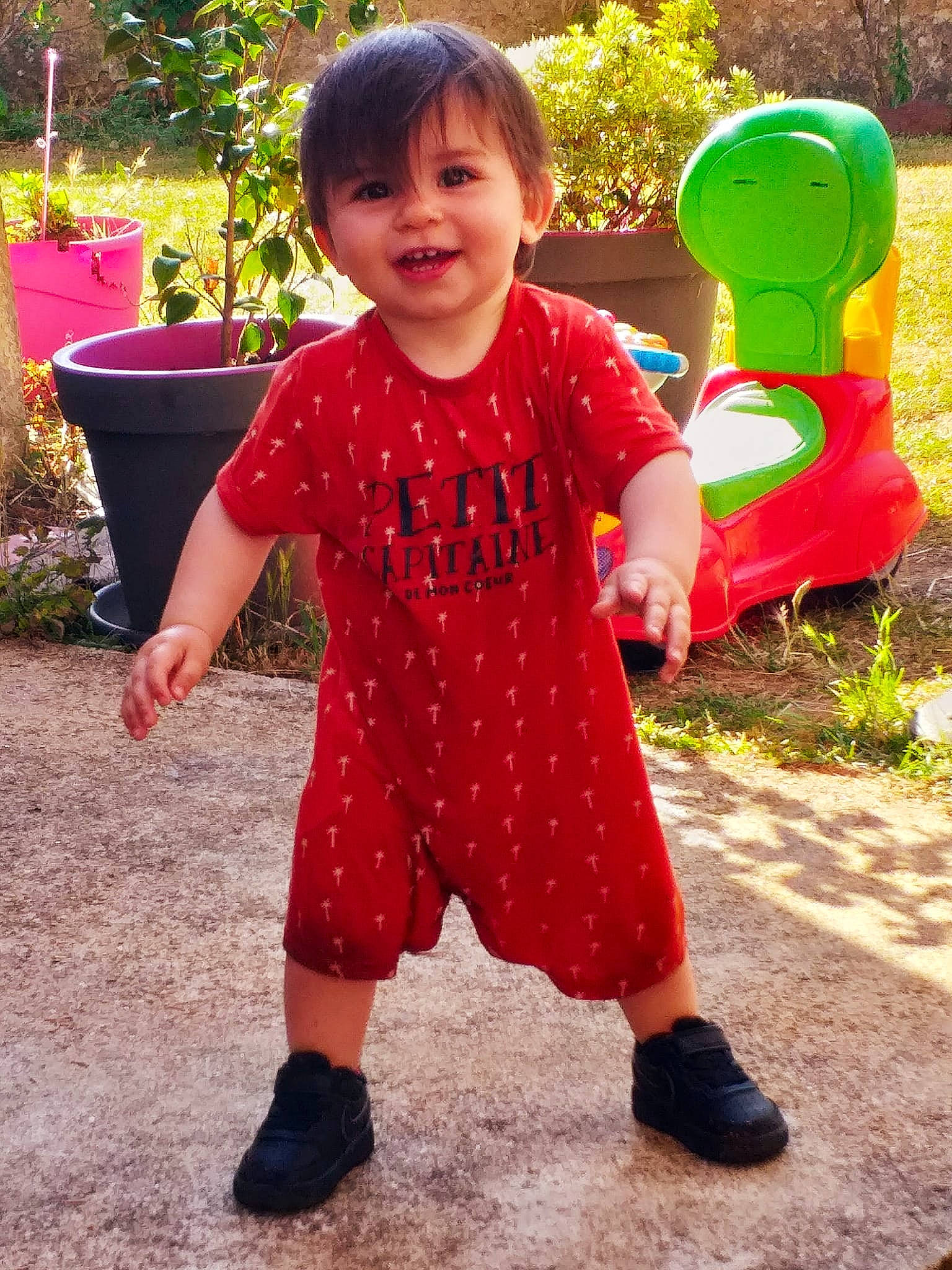Thymaël participe au concours pour gagner de l'argent avec cette photo : baby_toddler_clothing, child, eye, face, flowerpot, footwear, grass, green, happy, head, houseplant, joy, people_in_nature, person, pink, plant, red, shoe, sleeve, smile