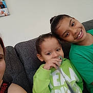 Tyanna joined the competition — help win amazing prizes! child, toddler, smile, pacifier, green_clothing, couch, indoor, family, person, sitting, happy, casual, home, portrait, young, cute, hair_bun, sweatshirt, relaxed, people