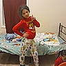 Tyanna joined the competition — help win amazing prizes! child, pajamas, bedroom, bed, plush_toy, cartoon, window, curtain, phone, pillow, floor, wood_floor, person, standing, socks, long_hair, playful, indoor, furniture, casual_clothing