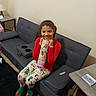 Tyanna is registered to the contest to win money with this photo: child, girl, smile, pajamas, red_shirt, couch, living_room, toy_container, barbie, table, lamp, happy, indoor, person, furniture, carpet, socks, holiday_theme, home, casual