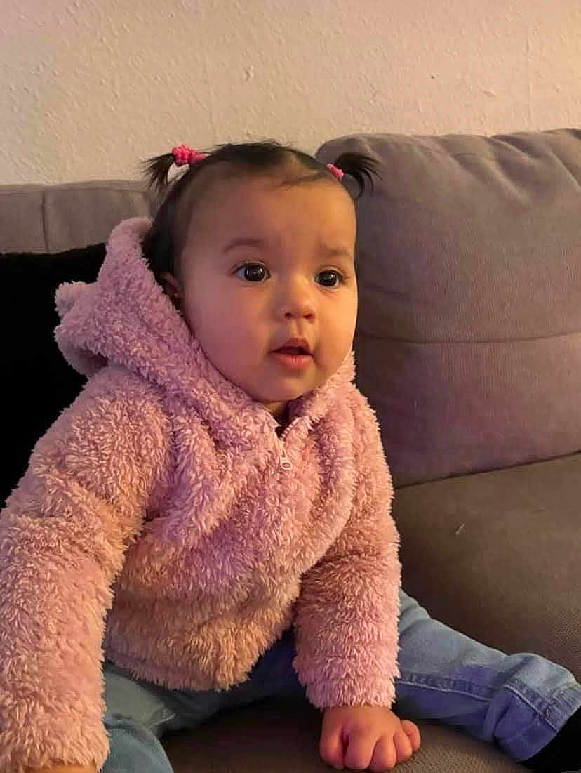 Rose joined the competition — help win amazing prizes! toddler, child, pink_jacket, pigtails, indoor, couch, sofa, curious, seated, casual_clothing, baby, portrait, young_child, cozy, cute, person, home, furniture, face, jeans