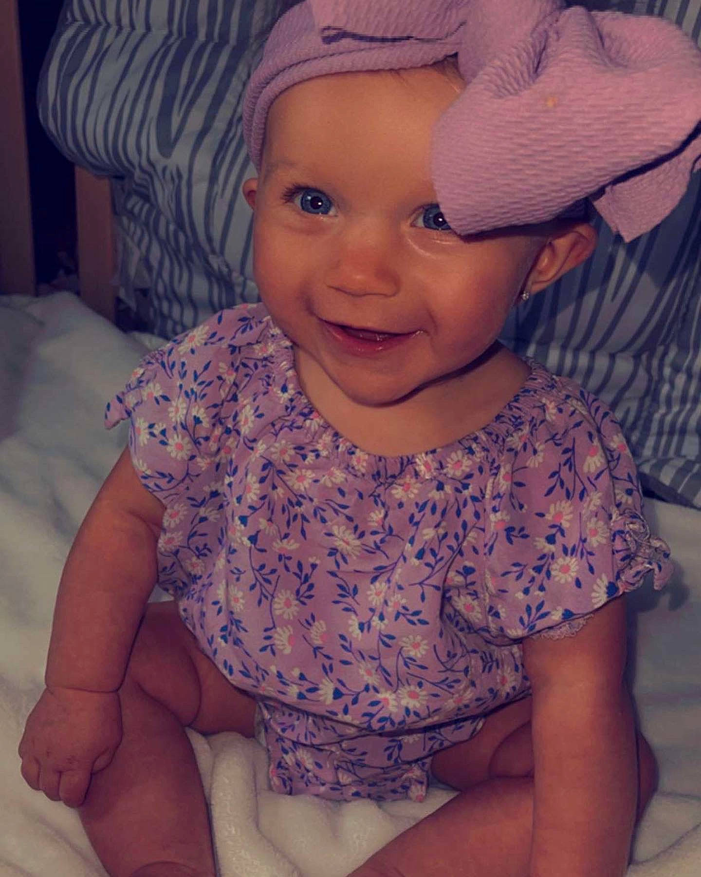 Davina is registered to the contest to win money with this photo: baby_toddler_clothing, cap, cheek, eye, eyebrow, facial_expression, happy, hat, headwear, iris, lip, mouth, nose, organ, person, photograph, pink, purple, skin, sleeve